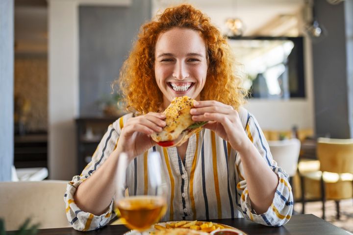 Young redhead girl eating a small sandwich
