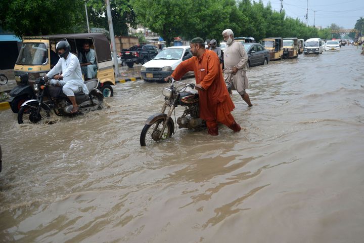 Commuters make their way through a flooded street after heavy rains in Karachi on September 13, 2022.