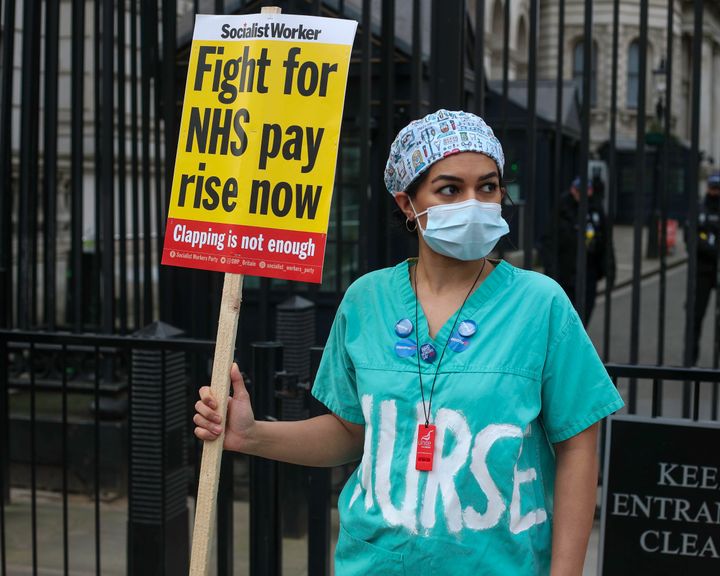Nurse holds a sign outside of Downing Street, Nurses are threatening to strike after being offered a 1% pay rise by the government 