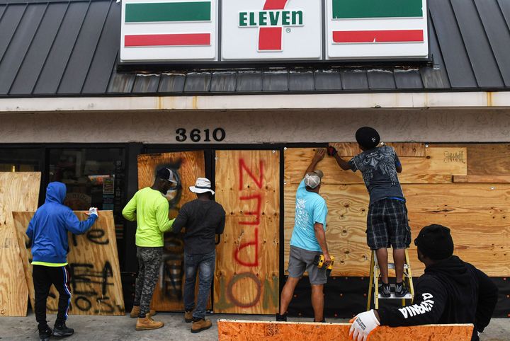 Workers board up a store with plywood in Daytona Beach Shores in Florida, as tropical Storm Nicole approached the coast of Florida Wednesday.
