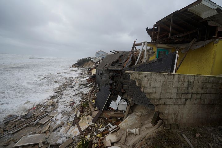 Parts of homes are seen collapsing on the beach due to the storm surge Thursday.