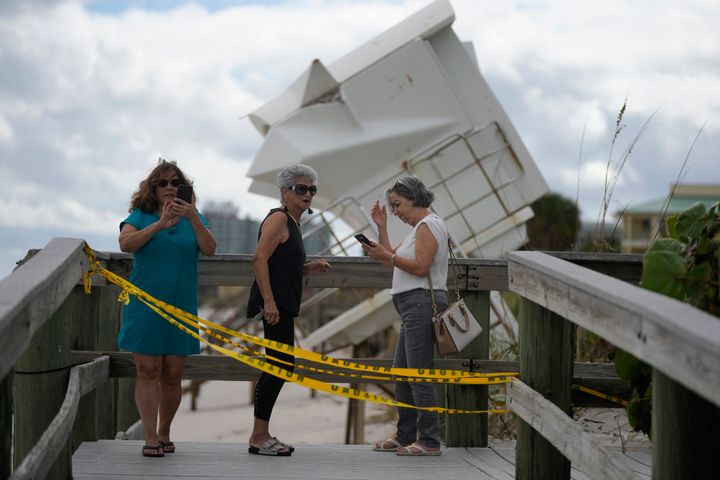 People visit the beach to investigate storm damage, including a lifeguard station that was displaced onto a dune, on Thursday in Vero Beach.