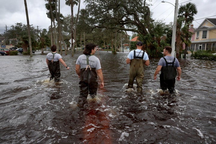 Members of the Daytona Beach Fire Department walk through flood water searching for people that may need help on Thursday in Daytona Beach.