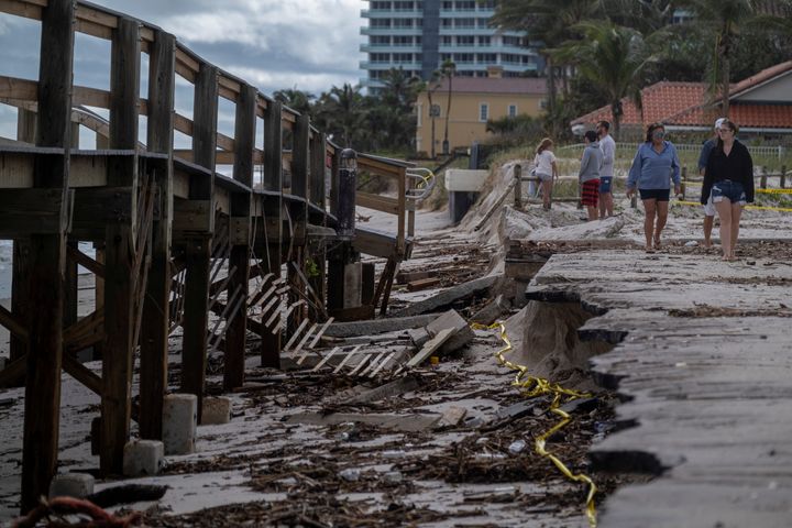 People walk by a damaged boardwalk in Vero Beach, Florida, on Thursday.