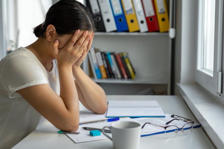 University student sadeness alone while sitting on table doing homework