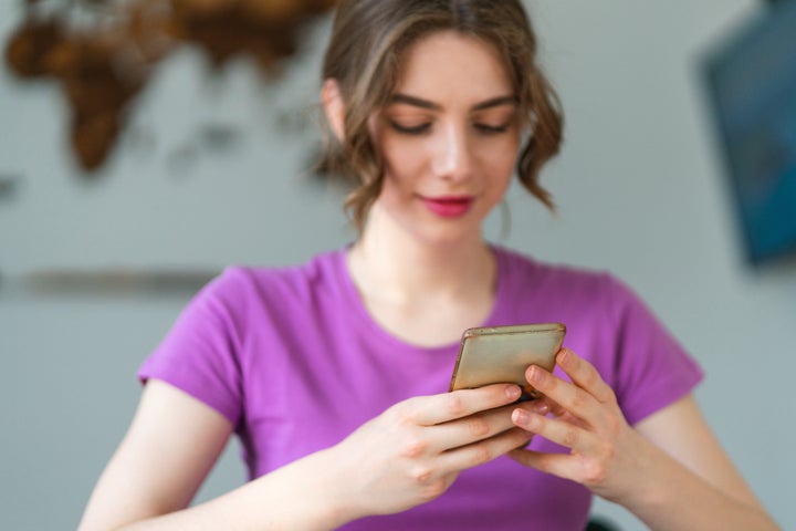 Close-up shot of a teenage girl scrolling social media on a mobile phone.