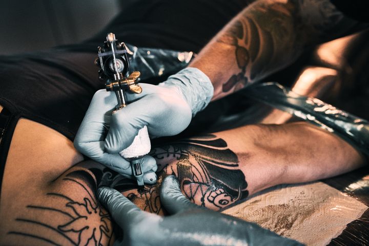 Making tattoo on customers shoulder