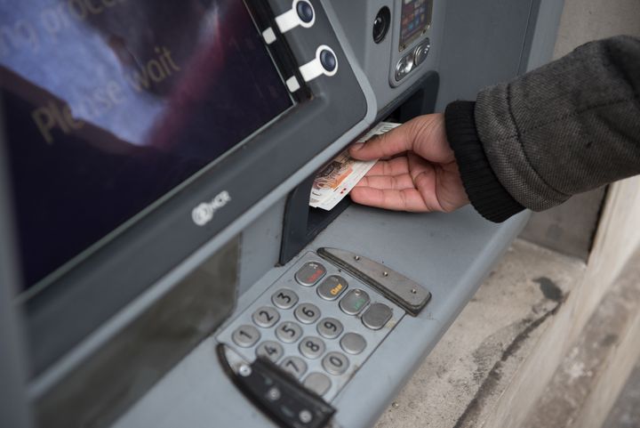 A member of the public withdraws cash from a cash machine.
