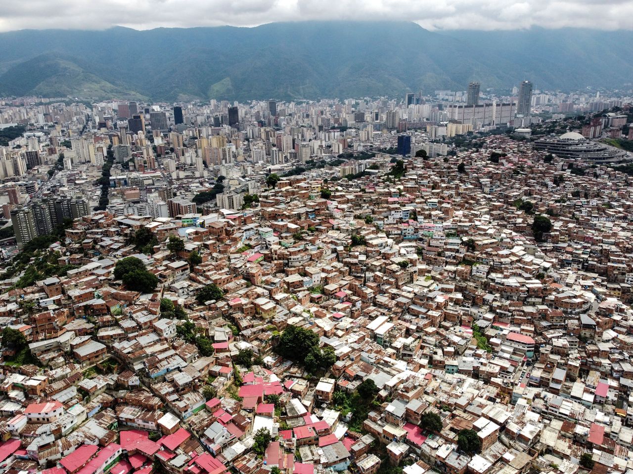 वेनेज़ुएला की राजधानी के पश्चिमी हिस्से में काराकास (दाएं) के दक्षिण-पश्चिम में अत्यधिक आबादी वाले पड़ोस और आवासीय और व्यावसायिक इमारतों को दिखाते हुए हवाई दृश्य।