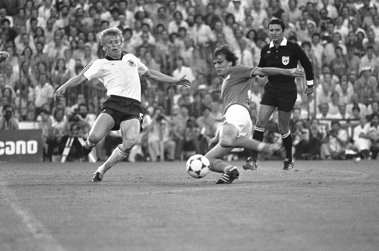 Ο Μάρκο Ταρντέλι της Ιταλίας προλαμβάνει την προβολή του Μπέρντ Φέρστερ της Δυτικής Γερμανίας και σκοράρει το δεύτερο γκολ της ομάδας του στον τελικό του 12ου Παγκοσμίου Κυπέλλου, στο Σαντιάγο Μπερναμπέου της Μαδρίτης, στις 11 Ιουλίου 1982. Η Ιταλία θα επικρατήσει με 3-1 κατακτώντας το κύπελλο για τρίτη φορά. Στο βάθος ο Βραζιλιάνος διαιτητής Αρνάντο Κοέλιο.