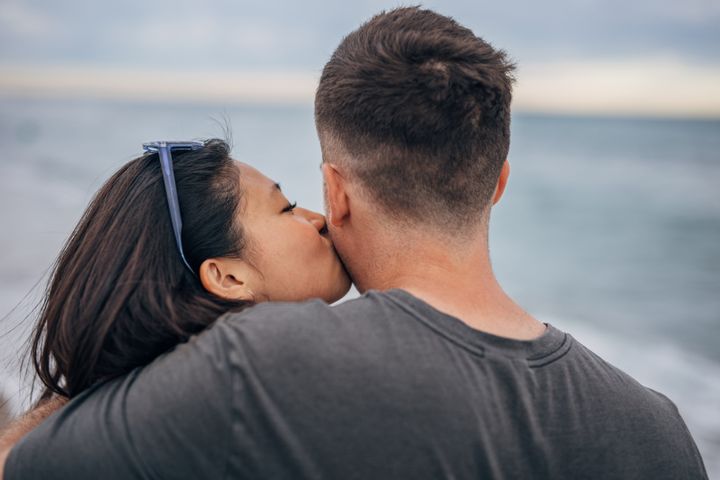 Young woman kissing boyfriend at a beach