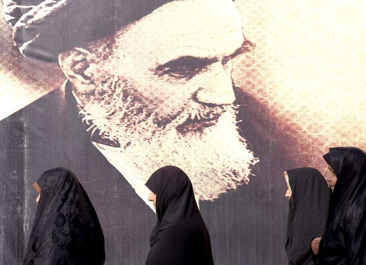 Ιρανές γυναίκες περνούν μπροστά από μια αφίσα του αείμνηστου ηγέτη του Ιράν Αγιατολάχ Ρουχολάχ Χομεϊνί κατά τη διάρκεια της τελετής επετείου της Ισλαμικής Επανάστασης του Ιράν στο νεκροταφείο Behesht Zahra, νότια της Τεχεράνης, 1 Φεβρουαρίου 2016.