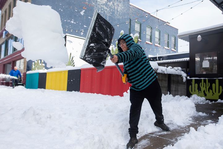 Jonathon Carmenatty, 21, clears snow from a sidewalk Friday in Buffalo, New York.