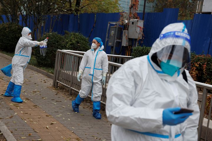 Εργαζόμενοι για την πρόληψη της πανδημίας με προστατευτικές στολές περπατούν έξω από μια αποκλεισμένη κατοικημένη περιοχή καθώς τα κρούσματα της νόσου του κοροναϊού (COVID-19) συνεχίζονται στο Πεκίνο, Κίνα, 18 Νοεμβρίου 2022.