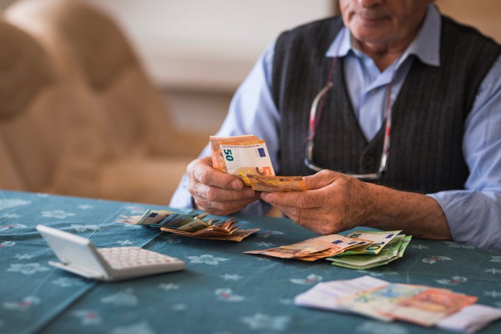 Un hombre cuenta dinero junto a una calculadora