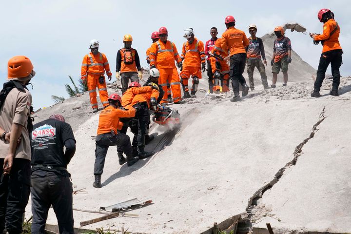 Rescuers cut through cement to recover the body of an earthquake victim from under the rubble of a collapsed building in Cianjur, West Java, Indonesia, on Nov. 22, 2022. 