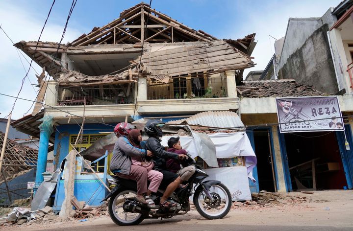 People ride a motorbike past a building damaged in Monday's earthquake in Cianjur, West Java, Indonesia, on Nov. 22, 2022. 