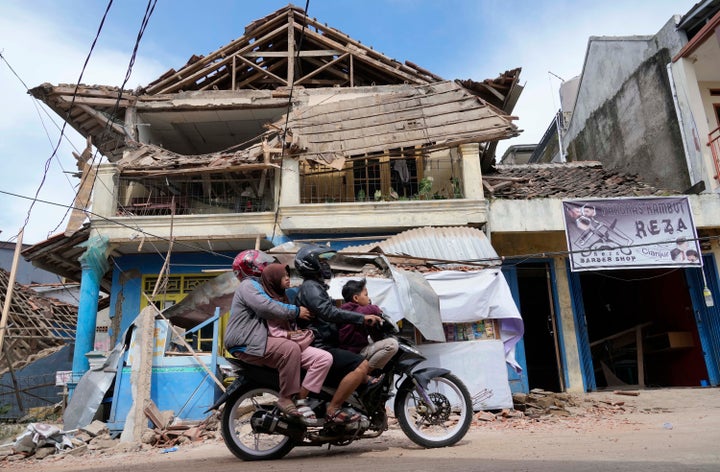 People ride a motorbike past a building damaged in Monday's earthquake in Cianjur, West Java, Indonesia, on Nov. 22, 2022.