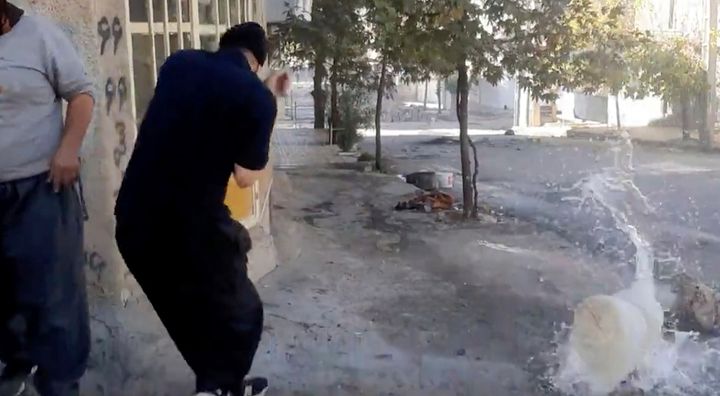 In this image from video provided by Hengaw Organization for Human Rights, a protester reacts after a water container was hit by a bullet during a protest in Javanroud, a Kurdish town in western Iran, on Nov. 21, 2022.