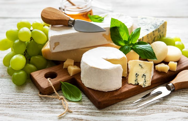 Various types of cheese on a white wooden background