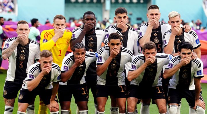 German players cover their mouths as they pose for a team group ahead of the FIFA World Cup Group E match at the Khalifa International Stadium, Doha. 