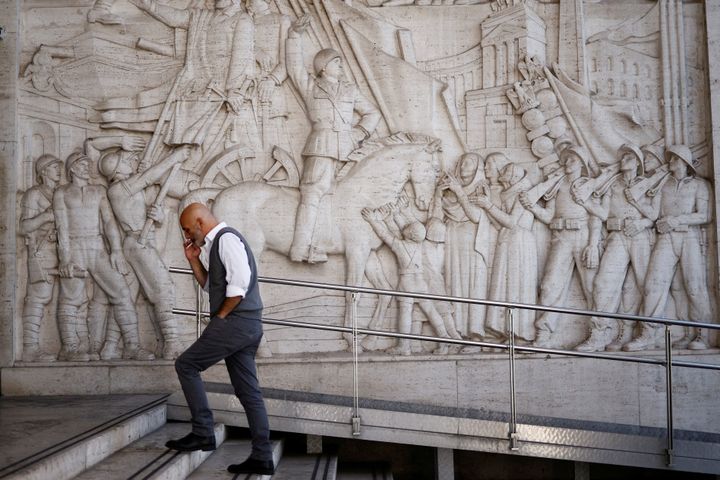 Ένας άνδρας περπατά μπροστά από ένα ανάγλυφο που απεικονίζει τον φασίστα ηγέτη Μπενίτο Μουσολίνι στη γειτονιά EUR της Ρώμης, Ιταλία, γνωστή για τη φασιστική αρχιτεκτονική της, 19 Οκτωβρίου 2022.
