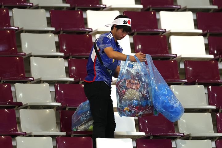 A Japanese fan clears rubbish from the stands after the match between Germany and Japan