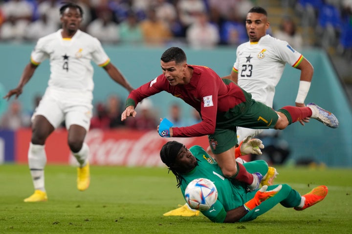 Portugal's Cristiano Ronaldo, up, falls over Ghana's goalkeeper Lawrence Ati-Zigi during the World Cup group H soccer match between Portugal and Ghana, at the Stadium 974 in Doha, Qatar, Thursday, Nov. 24, 2022. (AP Photo/Darko Bandic)