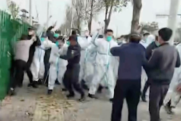 Online News Magazine In this photo provided Nov 23, 2022, security personnel in protective clothing attack a man during protest at the factory compound operated by Foxconn Technology Group who runs the world's biggest Apple iPhone factory in Zhengzhou in central China's Henan province. Employees at the world's biggest Apple iPhone factory were beaten and detained in protests over pay amid anti-virus controls, according to witnesses and videos on social media Wednesday, as tensions mount over Chinese efforts to combat a renewed rise in infections. (AP)