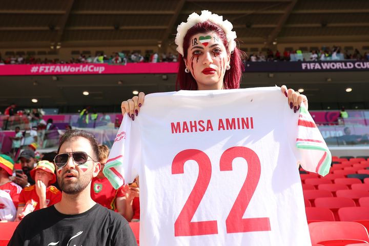 A female Iran fan holding the a shirt for Mahsa Amini who was killed by police brutality