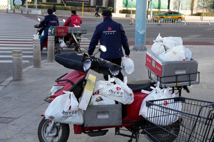 Delivery men prepare to deliver their orders for a supermarket in Beijing, on Nov. 25, 2022.