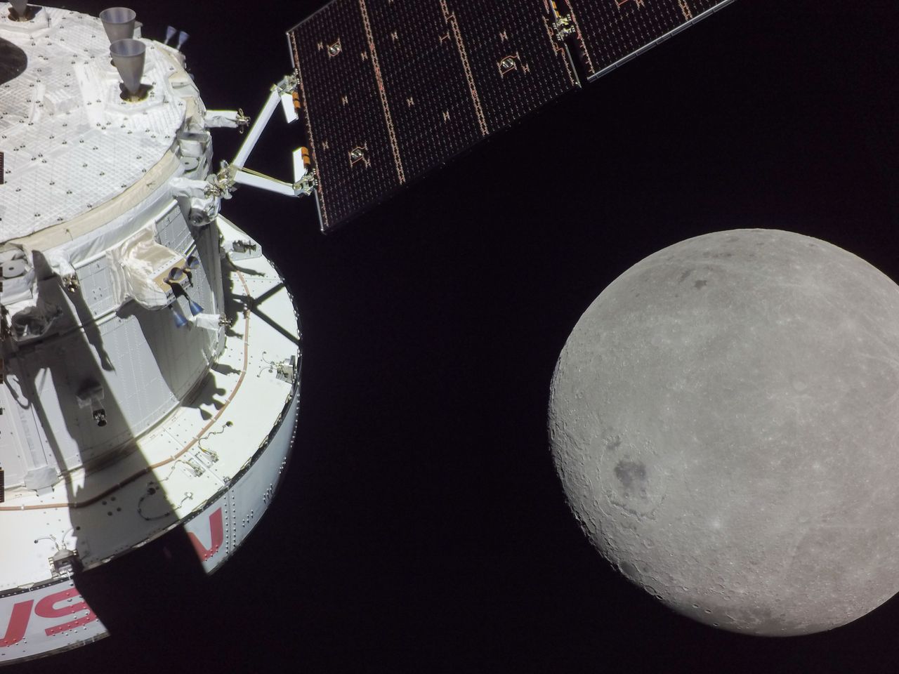 A portion of the far side of the moon looms large just beyond the Orion spacecraft in this image released Nov. 21, 2022, of the Artemis I mission. The darkest spot visible near the middle of the image is Mare Orientale.