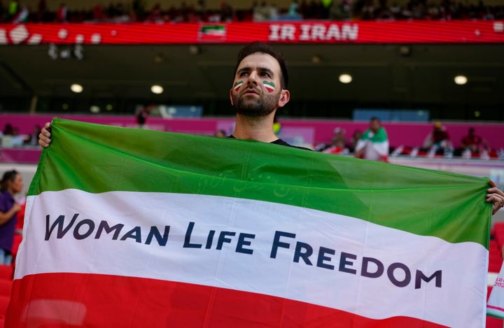 A soccer fan holds Iran's national flag on Friday with a message that supports the freedom for Iranian women in memory of Mahsa Amini, a woman who died while in police custody in Iran.