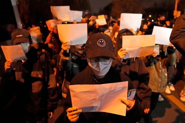 Protesters hold up blank papers and chant slogans as they march in protest in Beijing, on Nov. 27, 2022. Protesters angered by strict anti-virus measures called for China's powerful leader to resign, an unprecedented rebuke as authorities in at least eight cities struggled to suppress demonstrations Sunday that represent a rare direct challenge to the ruling Communist Party.
