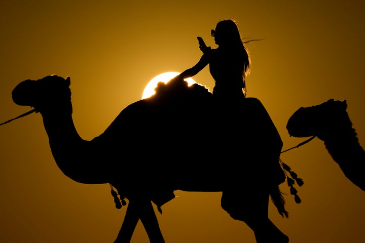 A woman looks at her photo while riding a camel in Mesaieed, Qatar, on Nov. 26, 2022.