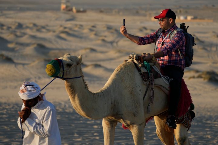 A man takes a selfie while riding camels in Mesaieed, Qatar, on Nov. 26, 2022.