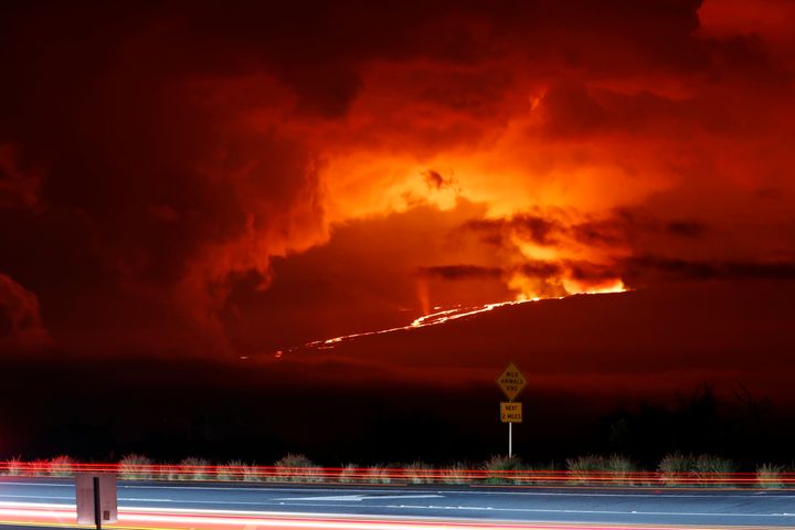 In this long camera exposure, cars drive down Saddle Road as Mauna Loa erupts in the distance, Monday, Nov. 28, 2022.