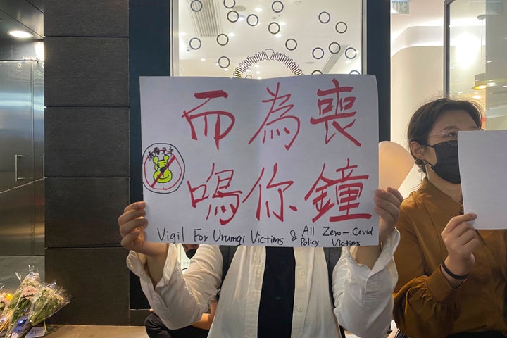 A protester holds up a banner commemorating the victims of a recent Urumqi deadly fire with the words "the death knell tolls for you" in Central in Hong Kong, on Nov. 28, 2022. 