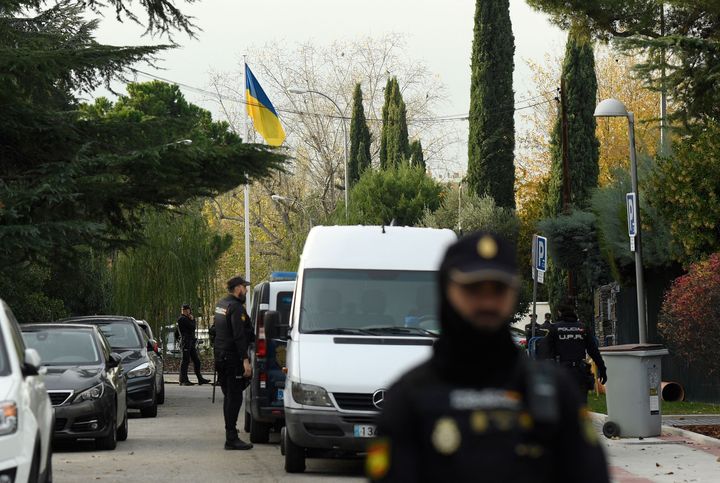 Spanish policemen stand next to an Ukrainian flag while securing the area after a letter bomb explosion at the Ukraine's embassy in Madrid on November 30, 2022. (Photo by OSCAR DEL POZO/AFP via Getty Images)