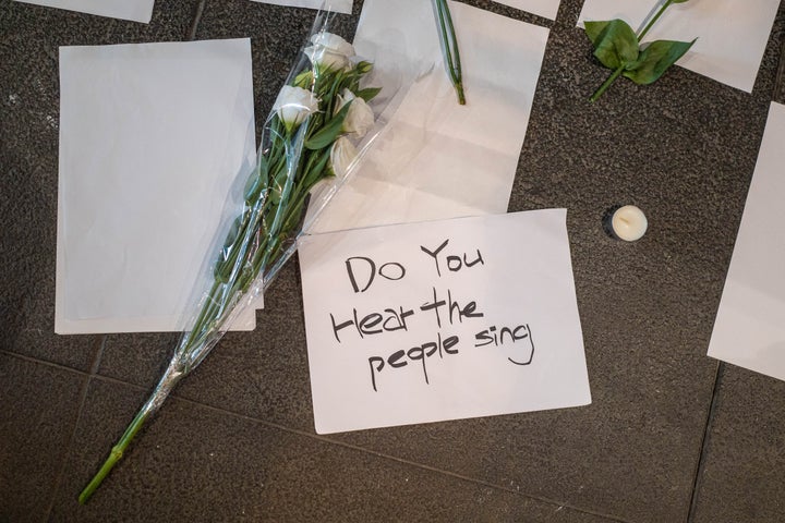 Memorial flowers and blank pieces of paper are seen next to a burning candle during the demonstration in Hong Kong on Nov. 28, 2022. 