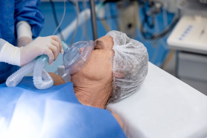 Senior patient in surgery breathing through an oxygen mask - operating room concepts