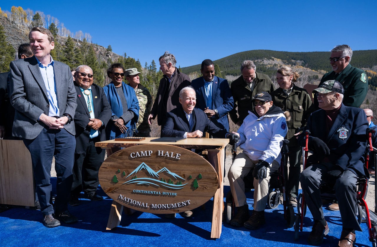 US President Joe Biden (C), surrounded by US Senator Michael Bennet (D-CO), US Senator John Hickenlooper (D-CO), US Representative Joe Neguse (D-CO), and additional guests, smiles after designating Camp Hale as a National Monument, at Camp Hale near Leadville, Colorado, on Oct. 12, 2022. 