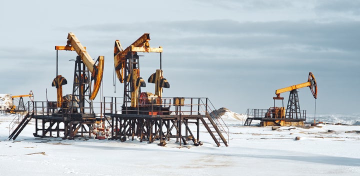 Oil frozen pump and snowy cold winter by sea coast, cloudy gray sky