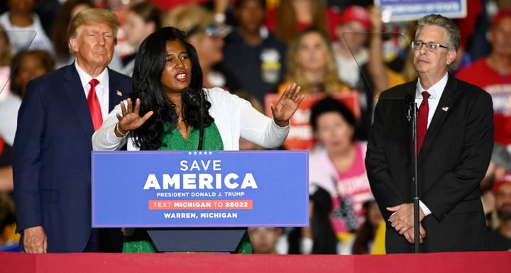 Former President Donald Trump, left, and Michigan Republican attorney general candidate Matt DePerno, right, listen as Michigan Republican secretary of state candidate Kristina Karamo addresses the crowd during a rally at the Macomb Community College Sports & Expo Center in Warren, Michigan, on Saturday, Oct. 1.