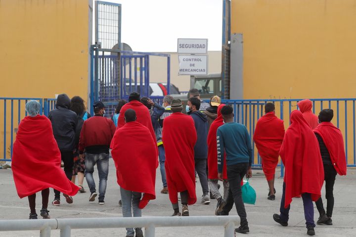 Mετανάστες περπατούν έξω από μια εγκατάσταση που έχουν προετοιμαστεί για αυτούς, συνοδευόμενοι από Ισπανούς αστυνομικούς, κοντά στα ισπανομαροκινά σύνορα, αφού χιλιάδες μετανάστες πέρασαν κολυμπώντας αυτά τα σύνορα τις τελευταίες ημέρες, στη Θέουτα της Ισπανίας, 21 Μαΐου 2021. REUTERS/Jon Nazca
