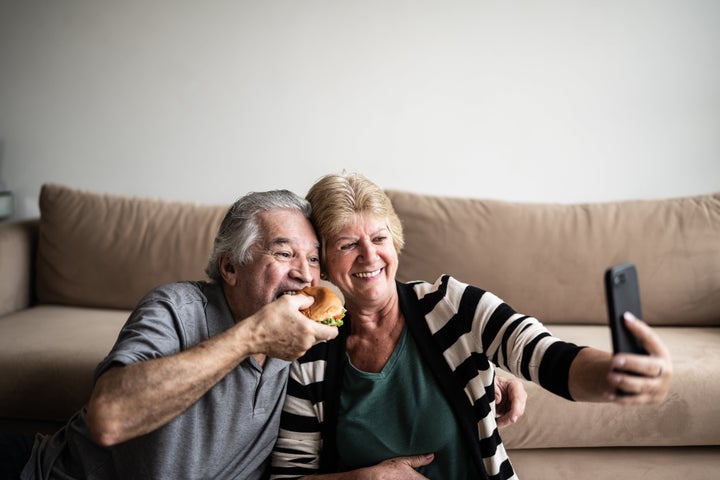 Senior couple eating fast food and doing a video call at home