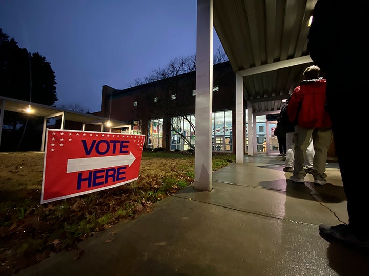 At a polling location in Johns Creek, Ga., voters in suburban Atlanta lined up before the polls opened on Tuesday, Dec. 6, 2022, to cast their ballot, undeterred by a 40-degree wind chill and steady rain. The line at Shakerag Elementary School moved swiftly. One voter called Election Day voting at this polling location, “smooth.” (AP Photo/Alex Sanz)