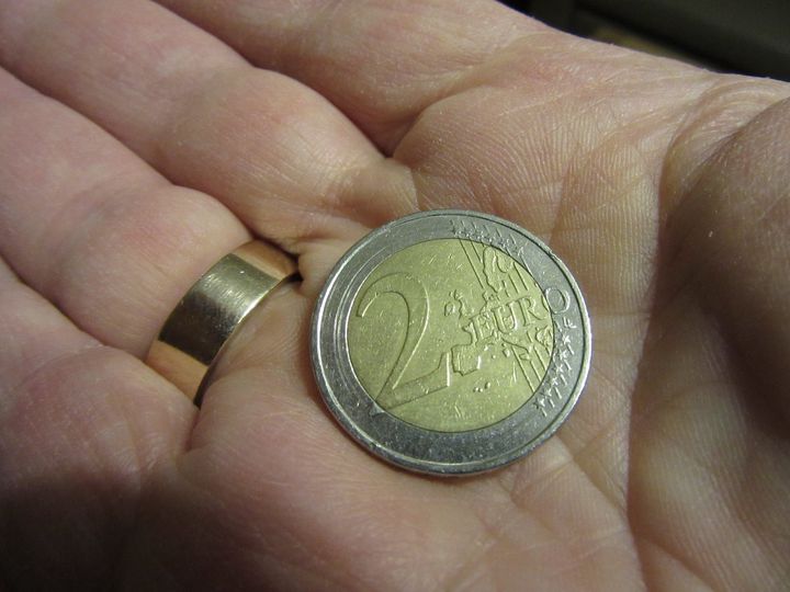 Una moneda de dos euros sobre la mano de una persona