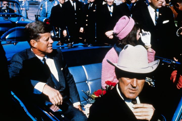 President John F. Kennedy, first lady Jacqueline Kennedy, and Texas Governor John Connally ride in a motorcade from the Dallas airport into the city shortly before Kennedy's assassination.