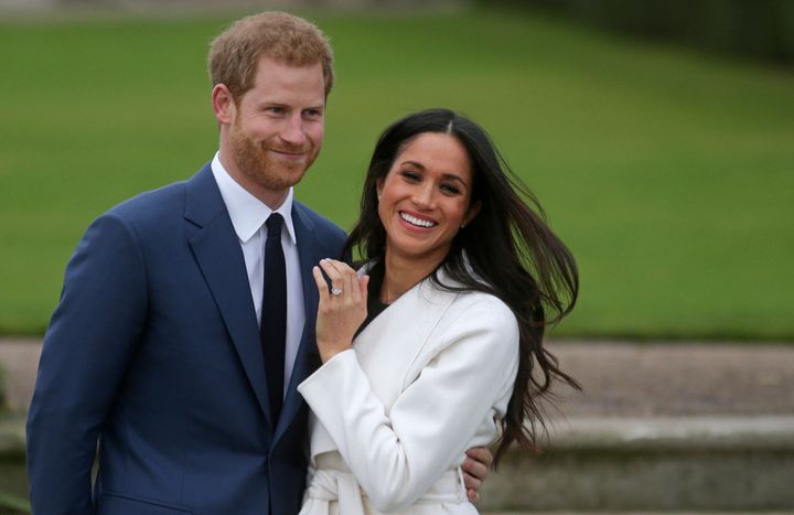 Prince Harry stands with his fiancée Meghan Markle as she shows off her engagement ring whilst they pose for a photograph in the Sunken Garden at Kensington Palace on Nov. 27, 2017. 